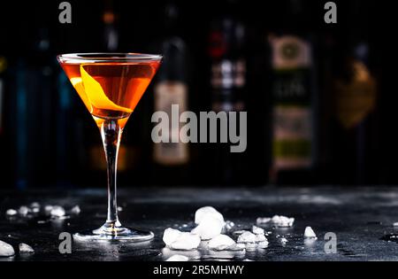 Cocktail alcolico Bobby Burns con whisky scotch, vermouth e liquore in vetro martini, sfondo del banco del bar scuro Foto Stock