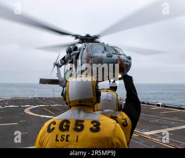 230423-N-EU502-3060 OCEANO PACIFICO (23 aprile 2023) - il compagno di Boatswain Seaman Edwin Falcon-Fernandez, di Boston, a destra, con il supporto del compagno di Boatswain 2nd Class Chase Canon, di Detroit, Dirige un elicottero MH-60R Sea Hawk assegnato a Helicopter Maritime Strike Squadron (HSM) 71 mentre parte dal ponte di volo dell'incrociatore missilistico guidato USS Mobile Bay (CG 53), 23 aprile 2023. Mobile Bay è in corso con la Carl Vinson Carrier Strike Group conducing Group Sail, che dimostra la capacità di aggregare rapidamente le unità del gruppo sciopero e offre l'opportunità di condurre un treno di avanzamento Foto Stock