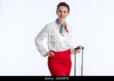 felice assistente di volo femminile elegante su sfondo bianco in uniforme con borsa trolley. Foto Stock