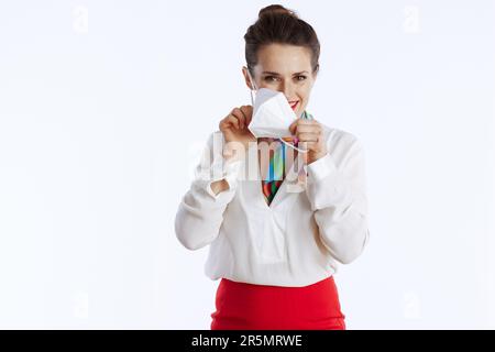 elegante e sorridente hostess d'aria femminile su sfondo bianco in uniforme indossando maschera ffp2. Foto Stock