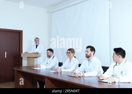 Dottore senior che tiene lezioni in sala conferenze con schermo di proiezione Foto Stock