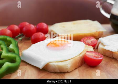 Toast gustosi con uova fritte, formaggio e verdure su tavola di legno, primo piano Foto Stock