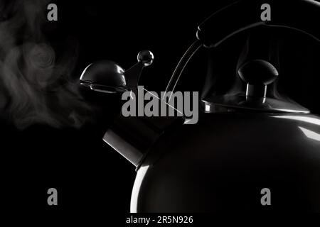 bollitore per tè con acqua bollente su sfondo scuro Foto Stock