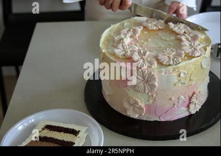 Le donne tagliano la torta di compleanno decorata su un tavolo bianco Foto Stock