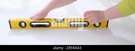 Le mani di lavoro controllano l'uniformità della parete con l'attrezzo speciale per la misurazione del livello Foto Stock
