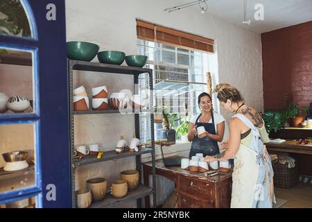 L'arte è un regalo che è meglio condiviso. due giovani donne che fanno tazze in uno studio di ceramica. Foto Stock