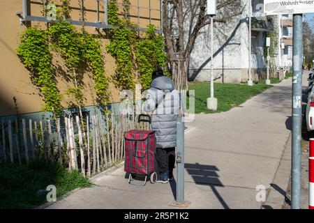 vienna, austria. 5 aprile 2023 urban shopper una donna è in piedi per strada con la sua borsa trolley fidata (la vita quotidiana in europa) Foto Stock