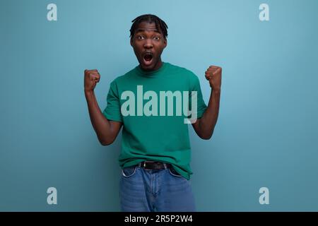 modello di sicura brunetta elegante uomo dalla pelle scura con lucchetti in una t-shirt alla moda su sfondo blu Foto Stock