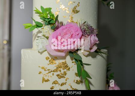 Torta nuziale a quattro livelli con fiori freschi e foglia d'oro Foto Stock