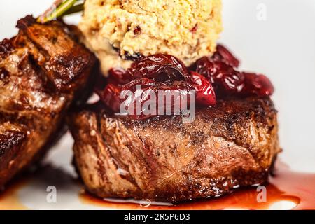 Un pasto sano di medaglioni di manzo con un lato di pomodori secchi servito su un piatto. Foto Stock