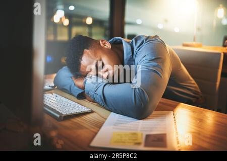 Ho appena riposato gli occhi... un bel giovane uomo d'affari che dormiva alla sua scrivania mentre lavorava a tarda notte in un ufficio moderno. Foto Stock