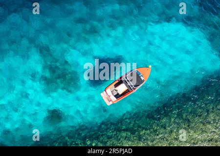 Piccolo motoscafo che galleggia su un'acqua cristallina turchese. Foto Stock