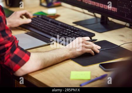 Immagine ravvicinata di mani maschili, designer grafico, retoucher che lavora con le foto, utilizzando tavoletta grafica e stilo, modificando le foto Foto Stock