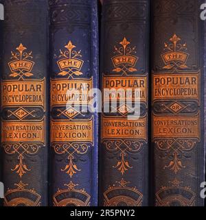 Volumi rilegati in pelle del popolare dizionario Encyclopedia o Conversations visualizzati su una libreria Foto Stock