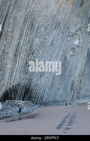 Turisti vicino alle scogliere giganti di Flysh sulla spiaggia di Itzurun a Zumaia, Paesi Baschi, Spagna Foto Stock