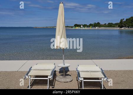 Zaton, Croazia - 18 maggio 2023 - la spiaggia di mare con ombrelloni a Zaton la mattina di una giornata di sole primaverile Foto Stock