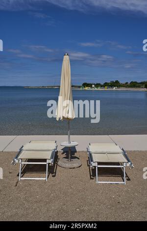 Zaton, Croazia - 18 maggio 2023 - la spiaggia di mare con ombrelloni a Zaton la mattina di una giornata di sole primaverile Foto Stock