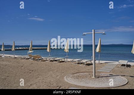 Zaton, Croazia - 18 maggio 2023 - la spiaggia di mare con ombrelloni a Zaton la mattina di una giornata di sole primaverile Foto Stock