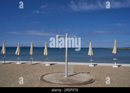 Zaton, Croazia - 18 maggio 2023 - la spiaggia di mare con ombrelloni a Zaton la mattina di una giornata di sole primaverile Foto Stock