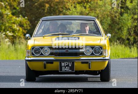 Stony Stratford, Regno Unito - Giugno 4th 2023: 1972 giallo FORD CORTINA auto classica in viaggio su una strada di campagna inglese. Foto Stock