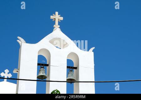 Una croce e campane sulla cima di una chiesa ortodossa imbiancata in Grecia iOS e un cielo blu sullo sfondo in Grecia iOS Foto Stock