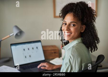 Donna d'affari sorridente che usa un notebook nel suo ufficio di casa Foto Stock