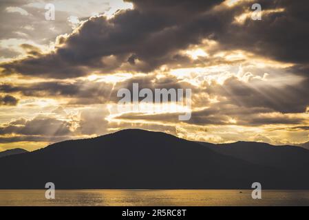 Raggi di sole che sbirciano tra le nuvole staccate viste da Lions Bay nella Columbia Britannica e che si affacciano sul mare tranquillo Foto Stock