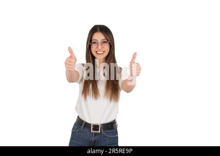 Mi piace, gioiosa ragazza bruna caucasica che mostra due pollici in alto. Fotocamera sorridente. Ritratto di bella signora, sfondo bianco isolato. Foto Stock