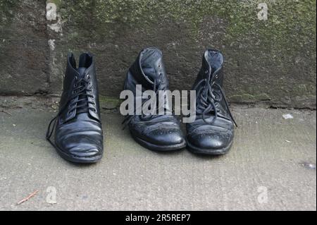 Vecchie scarpe in pelle nera per strada. Scarpe nere da uomo. Foto Stock