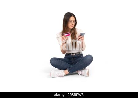 Online banking, ragazza caucasica con carta di credito e utilizzo di smartphone per l'online banking. Sfondo bianco isolato, spazio di copia. Shopping online. Foto Stock