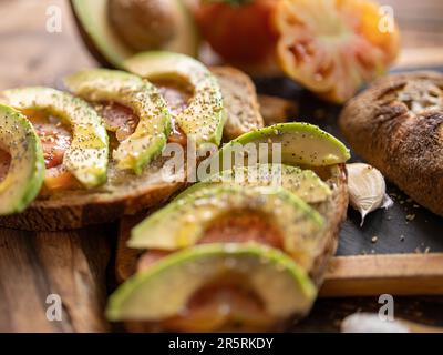 Pasta di segale appena sfornata pane artigianale biologico affettato con pomodoro, aglio, olio EVO, avocado, sale Foto Stock