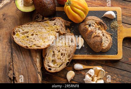 Pasta di segale appena sfornata pane artigianale biologico affettato con pomodoro, aglio, olio EVO, avocado, sale Foto Stock