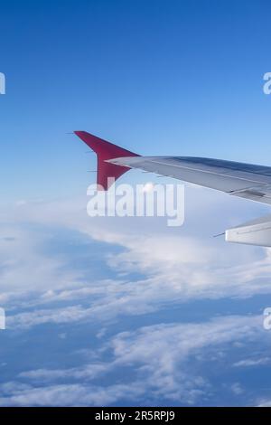 foto verticale l'ala di un aereo volante sullo sfondo delle nuvole Foto Stock
