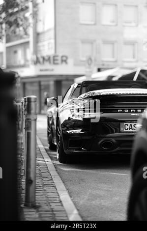 Una foto in scala di grigi di un'auto Porsche parcheggiata in strada. Foto Stock
