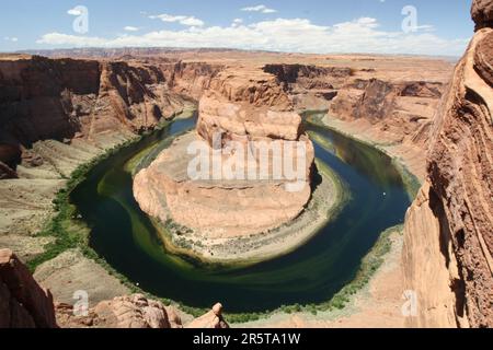 Vista aerea dell'iconica curva a ferro di cavallo sul fiume Colorado in Arizona, con il terreno roccioso dell'area circostante visibile Foto Stock