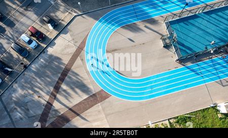 Pista da corsa blu sul campo sportivo pubblico accanto a un campo da calcio e da basket, vista dall'alto, fotografia dei droni, vista aerea Foto Stock