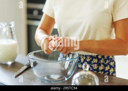 Chiudere la mano rompendo un uovo all'impasto per la frittella. Ingredienti per focaccia, torta, pizza, ravioli, pasta. panetteria, libro di cucina, blog di cucina. Foto Stock