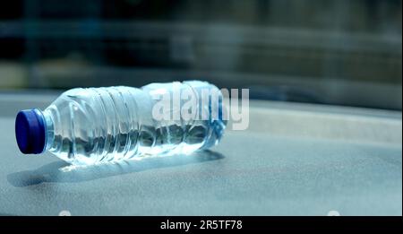 una bottiglia di acqua minerale sul cruscotto dell'auto. L'acqua in bottiglia è stata lasciata in macchina per molto tempo. Foto Stock