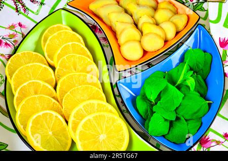 Concetto con frutta fresca, verdura e spezie verdi. Foglie di limone, zenzero e menta in ciotole colorate. Foto Stock