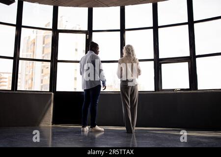 Agente immobiliare Lady e uomo africano parlando in ufficio Foto Stock