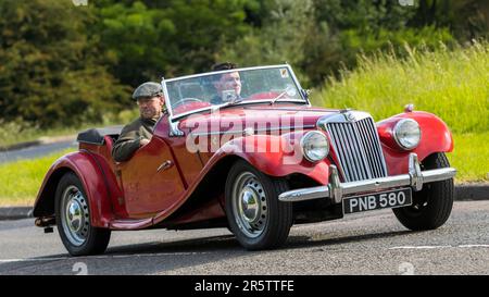 Stony Stratford, Regno Unito - Giugno 4th 2023: 1954 Red MG auto sportiva classica auto in viaggio su una strada di campagna inglese. Foto Stock