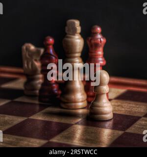 Quattro pezzi di scacchi in legno sono posizionati fianco a fianco su una classica scacchiera, pronta per un gioco di strategia Foto Stock