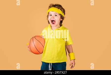 Simpatico giocatore di basket con palla da gioco. Piccolo giocatore di basket in abbigliamento sportivo. Stile di vita sportivo e concetto di infanzia. Bambino con basket ba Foto Stock