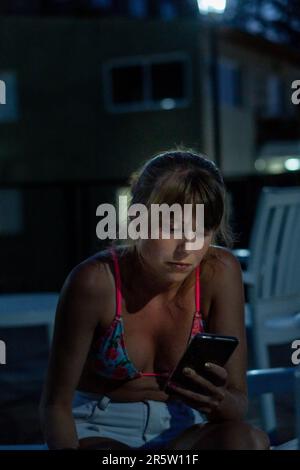 Una giovane donna adulta è all'aperto, utilizzando un telefono cellulare in mano Foto Stock