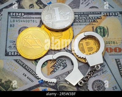 Un'immagine ravvicinata di una collezione di manette in metallo d'argento, una moneta d'oro e una moneta Bitcoin d'oro che si adagia su uno sfondo nero Foto Stock