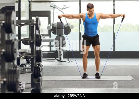 Ritratto completo di un tipo muscolare che si esercita con una fascia di resistenza in palestra Foto Stock