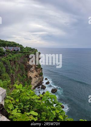 Una vista panoramica di una lussureggiante scogliera ricoperta di muschio verde che si affaccia sulla vasta distesa dell'oceano Foto Stock