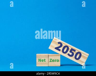 La frase net zero 2050 scritta su blocchi di legno su sfondo blu. Foto Stock