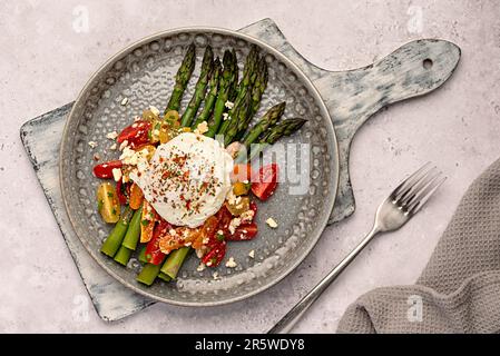 Fotografia alimentare di prima colazione, uova in camicia, asparagi, pomodoro, insalata, formaggio feta, dieta paleo, naturale, keto, stile di vita Foto Stock