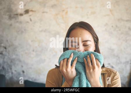 La fragranza ci ricorda che i ricordi non sono mai dimenticati. una giovane donna che odora il bucato appena lavato a casa. Foto Stock